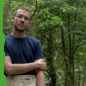 Photo of Jaka Skapin, standing, in front of greenery/forest.